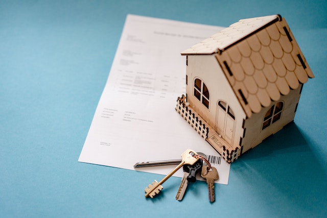 a home figurine and house keys resting on a contract
